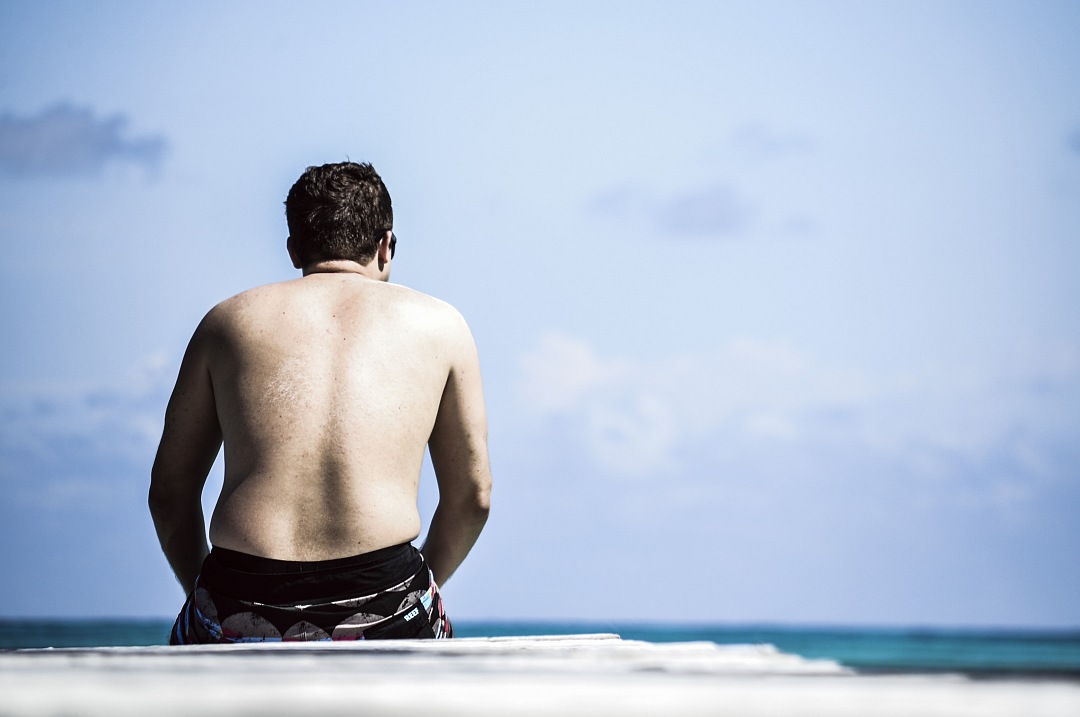 a man sitting on a surfboard looking out at the ocean