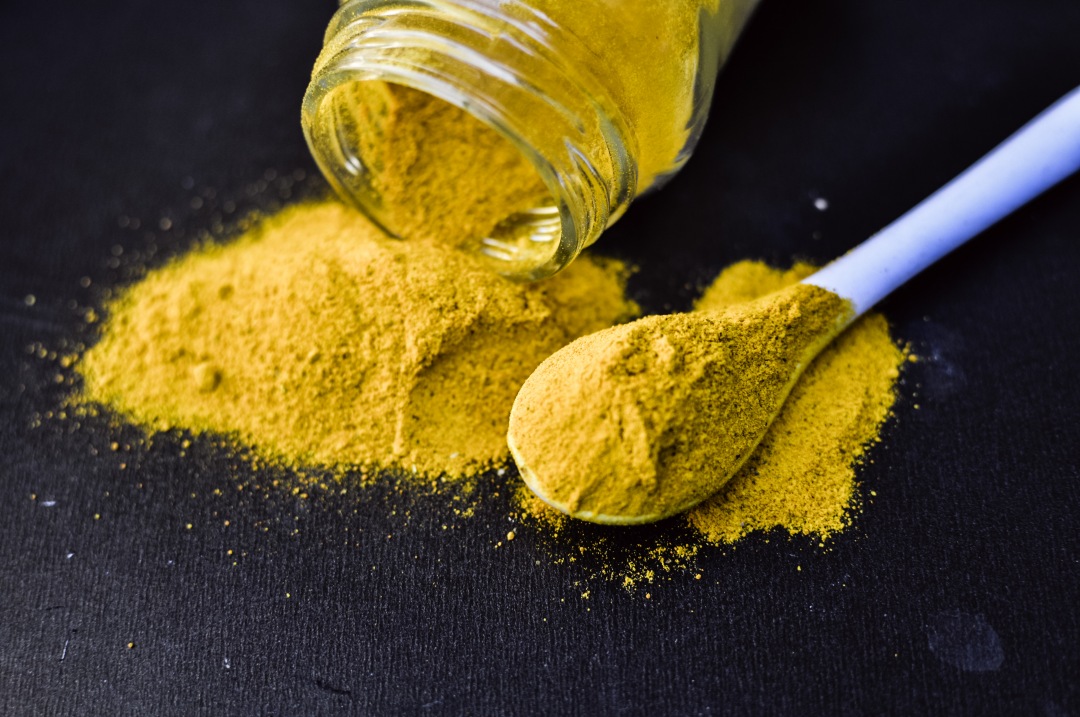 heap of yellow curcuma turmeric spices powder isolated on Black background