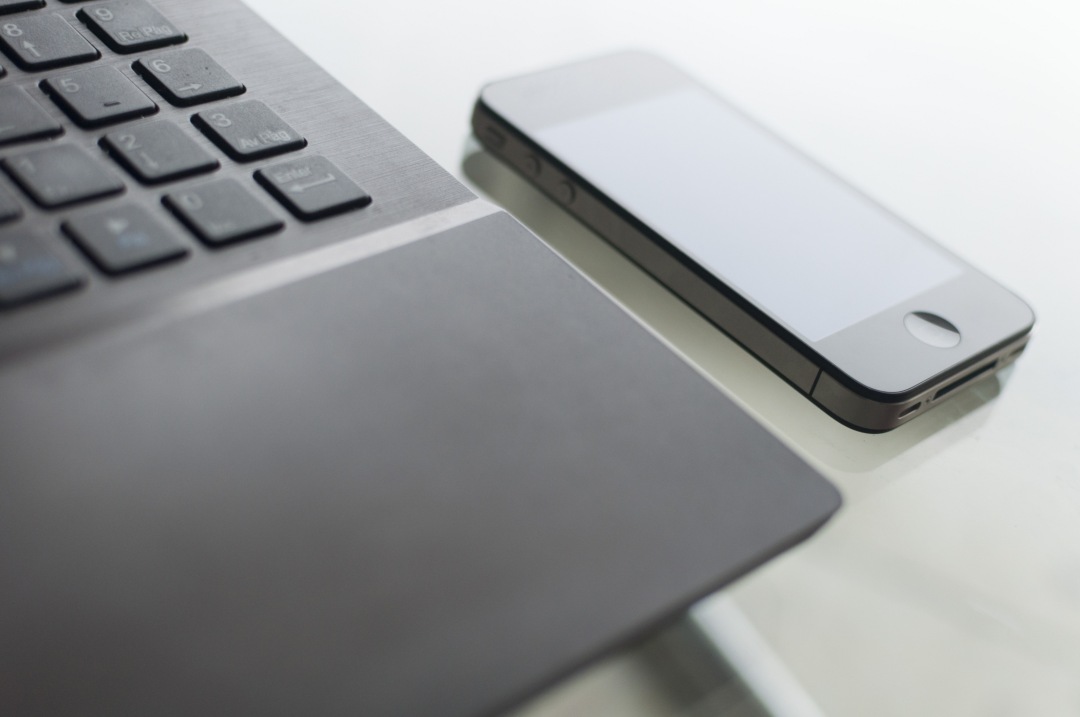 laptop with apple smart phone on glass table