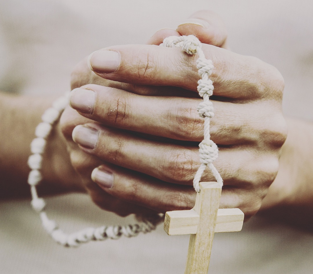 a person holding a wooden cross with a rope