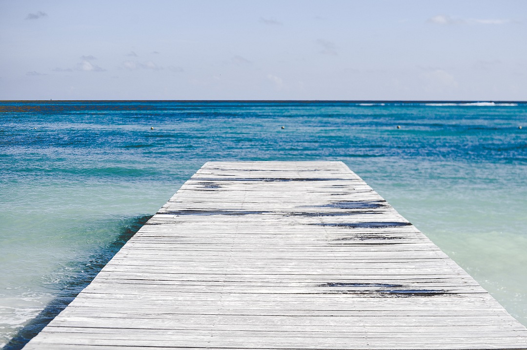 a wooden dock in the ocean with a blue sky