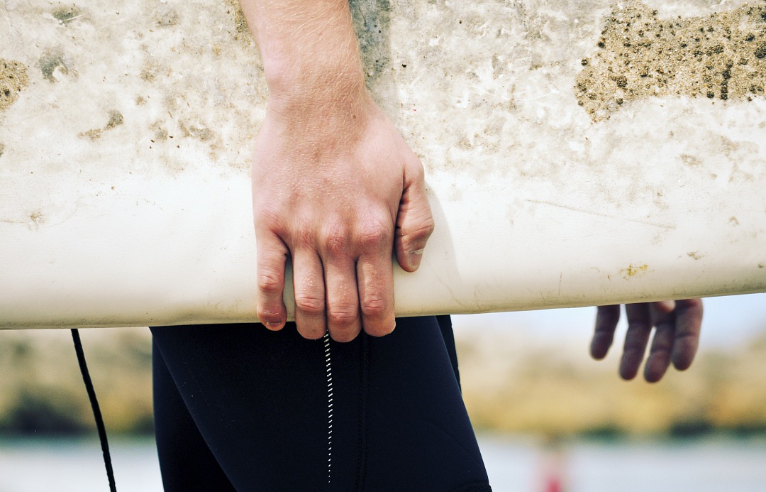 hand and Board of surfer walking on the beach