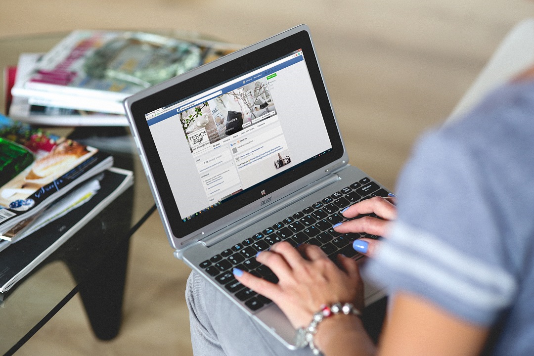 Woman navigate facebook page with laptop