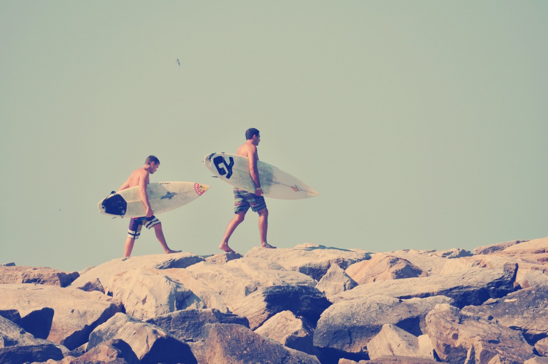Capture the essence of coastal adventure with this stunning image of two surfers strolling along a rugged rocky beach, surfboards in hand. Perfect for travel blogs, adventure sport promotions, and lifestyle articles, this scene encapsulates the thrill of surfing and the beautiful interplay between land and sea. Ideal for websites focusing on beach activities, surfing gear, or vacation planning, this image brings a sense of freedom and excitement to any project.