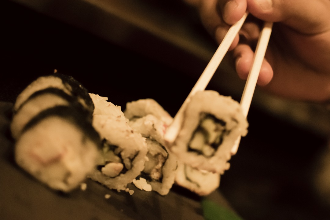 person taking sushi with sticks
