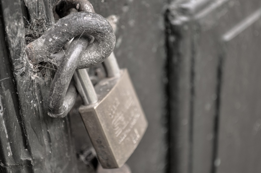 Discover the intricate details of a sturdy lock on a door, secured with a heavy-duty chain. This image captures the essence of safety and protection, making it ideal for articles or content related to home security, locksmith services, or safety protocols. Perfect for illustrating themes of security and resilience.
