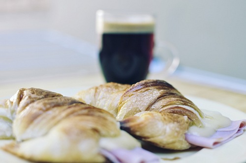 Fresh croissants with ham and cheese on plate and coffee cup