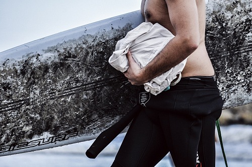 surfer walking with his board on the beach