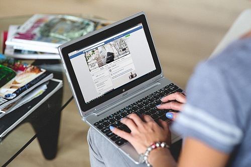 Woman navigate facebook page with laptop